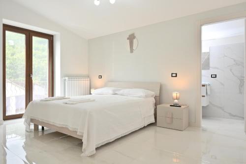 a white bedroom with a white bed and a window at FarmVille B&B in Moliterno