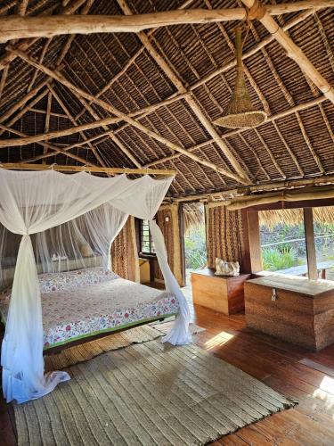 a bedroom with a bed with a mosquito net at Bone Idle, Lamu Beach Home in Lamu