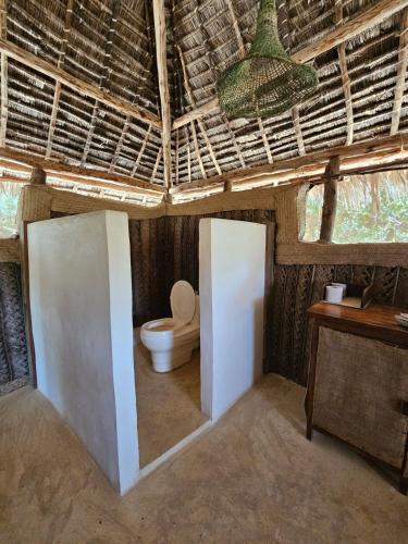 a bathroom with a toilet in a hut at Bone Idle, Lamu Beach Home in Lamu