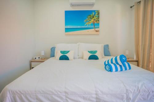 a bedroom with a white bed with blue and white pillows at Chiquitos Apartments in Savaneta