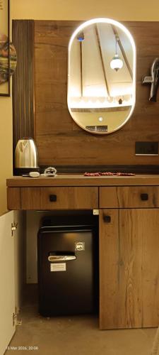 a bathroom with a mirror and a small refrigerator under a counter at Om Niwas Bhunga in Bhuj