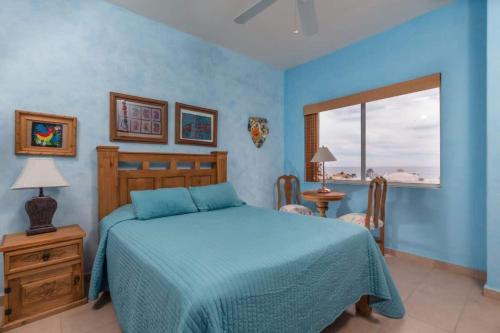 a blue bedroom with a bed and a window at Serene & Warm 3rd Level Condo - Corona del Mar 302 in Puerto Peñasco