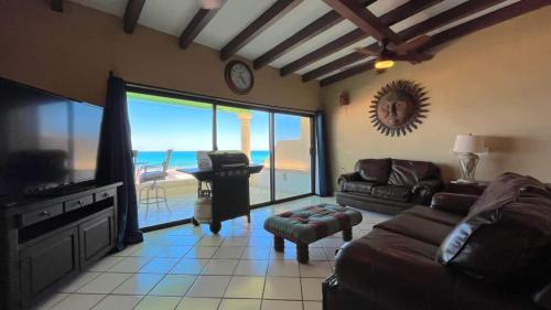 a living room with a couch and a television with a view of the ocean at Beautiful Beachfront Condo Las Olas II 11 in Puerto Peñasco