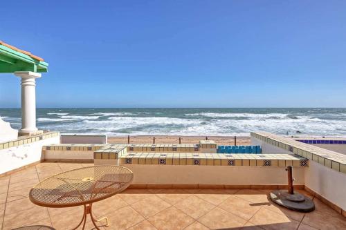 a table and a chair on a balcony overlooking the ocean at Cozy Beachfront Condo Las Olas II 10 in Puerto Peñasco