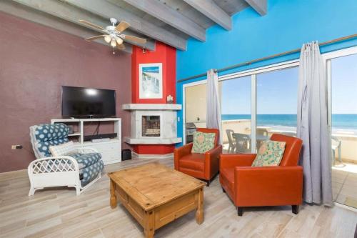 a living room with chairs and a television and a table at Cozy & Beautiful Beachfront Condo Las Olas II 2 in Puerto Peñasco