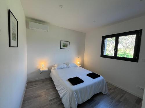 a bedroom with a white bed and a window at Gîte des Lauriers Roses in Laurac-en-Vivarais