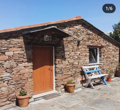 a stone cottage with a wooden door and a bench at Casa da Eira in Pinheiro de Coja