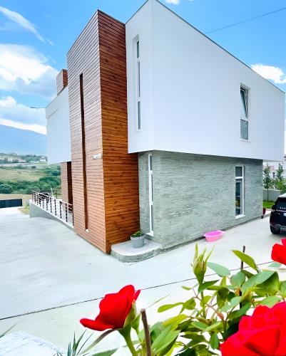 a house with red flowers in front of it at Farka Lake Luxury Villa in Tirana