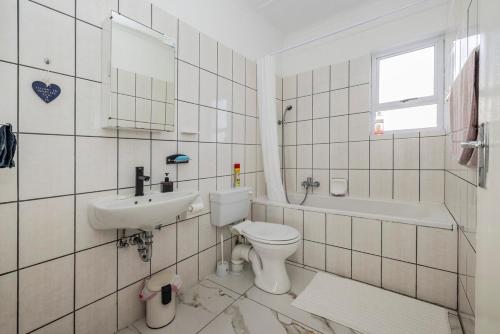 a white tiled bathroom with a toilet and a sink at Namclassics in Langstrand