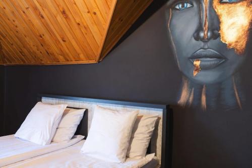 a bedroom with a painting of a face on the wall at Pensiunea Dezire in Baile Unu Mai