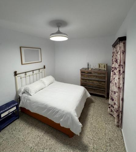 a white bedroom with a bed and a dresser at Mil House in Cómpeta