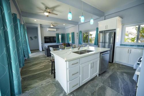 a kitchen with white cabinets and a sink at Villa Armoniosa Ocean View 2BR w/ Beachfront Pool - Upper Level in Placencia