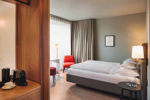 a hotel room with a bed and a red chair at Hotel am See in Hard