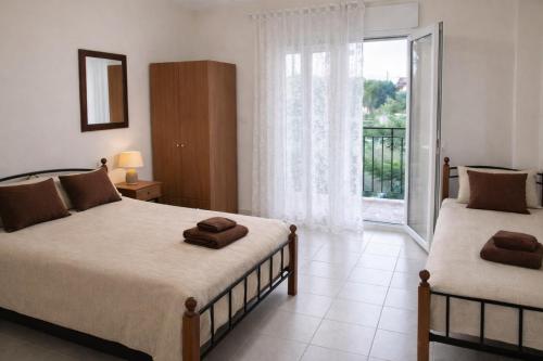 a bedroom with two beds and a large window at Noufara Apartments in Nea Mesangala