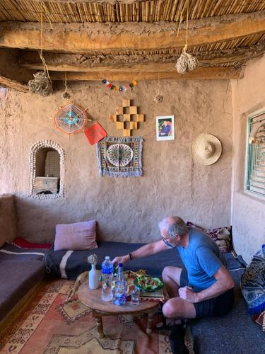 a man sitting at a table in a living room at Dar Nomad Tagounite in Zagora