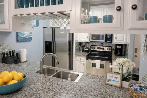 a kitchen with white cabinets and a sink with a bowl of fruit at Swanky 2 Bedroom, Easy Walk to Beach Mar y Sol II # 1 in South Padre Island