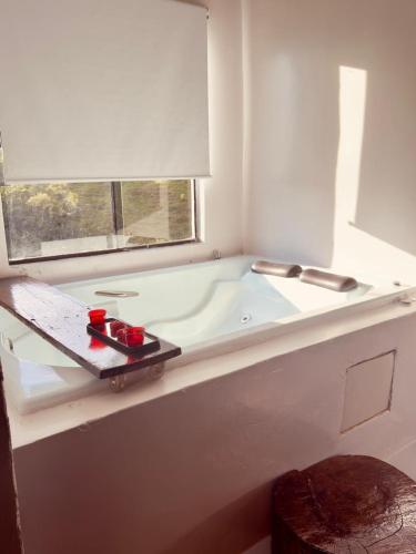 a white bathroom with a tub with a window at Chalè Aurora do vale in Cobras