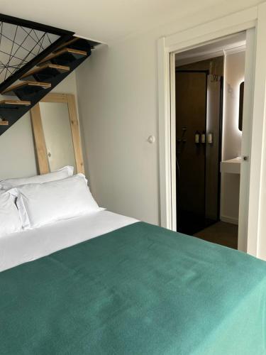 a bedroom with a white bed with a green blanket at Cá Por Casa Pico-Faia in Prainha de Baixo