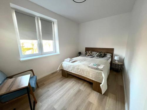 a small bedroom with a bed and a window at Campus Biebrza - apartamenty biebrzańskie in Osowiec