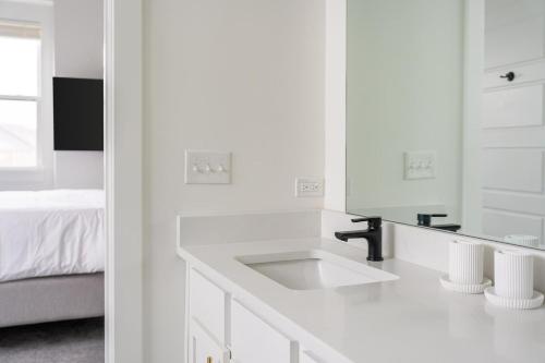 a white bathroom with a sink and a bed at Landing Beautiful 2BD in Lees Summit in Lees Summit