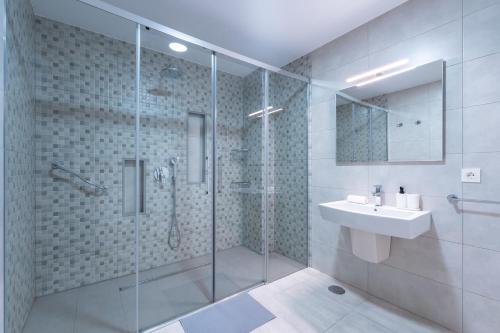 a bathroom with a glass shower and a sink at Villa Dasil in San Pedro