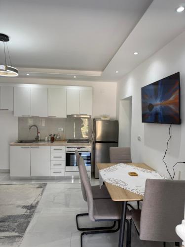 una cucina con mobili bianchi e un tavolo con sedie di Peaceful House a Përmet