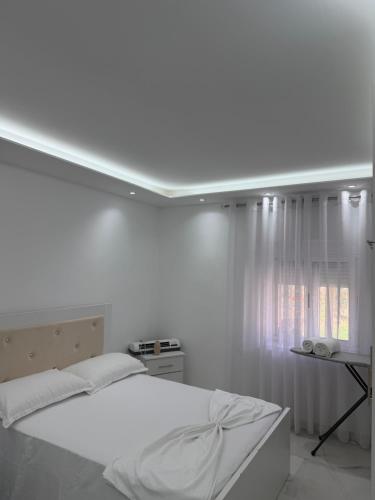 a white bedroom with a bed and a window at Peaceful House in Përmet