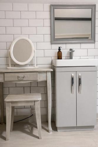 a bathroom with a sink and a mirror and a stool at The Red Lion & Cellar Room, Betchworth in Betchworth