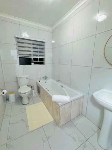 a bathroom with a tub and a toilet and a sink at Brytelight Luxe 1 Bedroom in Rustenburg