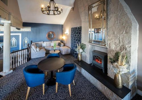 a living room with a fireplace and a table and chairs at Inn On The Coast in Portrush