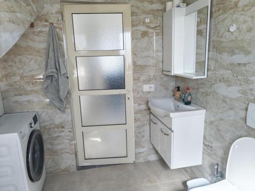 a bathroom with a sink and a washing machine at Ariona apartment in Draç