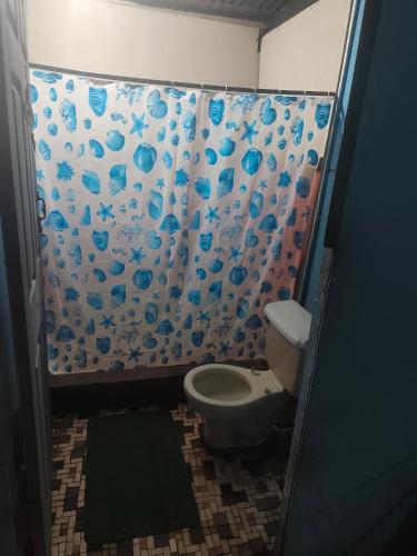 a bathroom with a shower curtain with a toilet at Casa de playa MC in Quepos