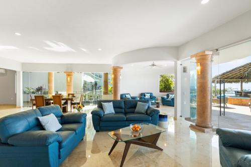 a living room with blue couches and a table at Luxe 3 King BR Villa | Infinity Pool + 220° Views in Puerto Vallarta