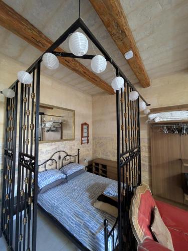 a bedroom with a black canopy bed with blue pillows at Paddy's Studio in Il-Ħamra