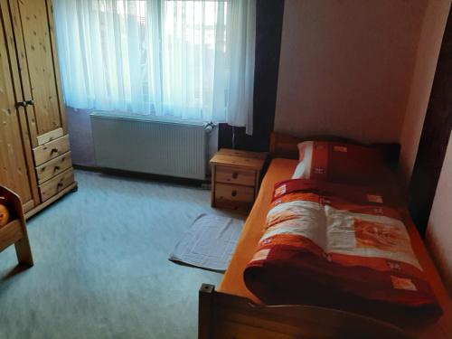 ein Schlafzimmer mit einem Bett, einer Kommode und einem Fenster in der Unterkunft Ferienwohnung Freiling in Wilhelmshütte