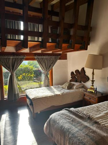 a bedroom with two beds and a large window at Rustic Escape Between Valle & Avándaro in Valle de Bravo