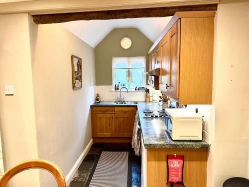 a kitchen with wooden cabinets and a sink and a window at Manor Cottage in Cavendish