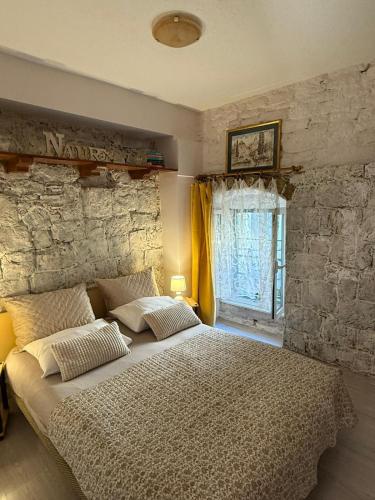 a bedroom with a large bed and a stone wall at Ankora in Omiš