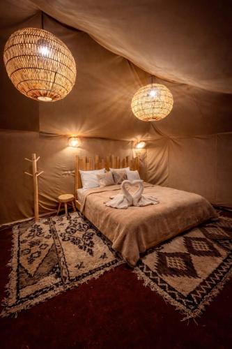 a bedroom with a bed in a tent with two lights at Sahara wellness camp in Merzouga