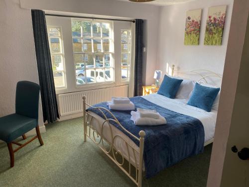 a bedroom with a bed and a chair and a window at The Phelips Arms in Montacute