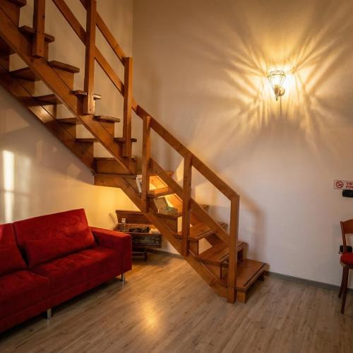 a living room with a staircase and a red couch at Casa Tziu Predu - Centro Nuoro - B&Brothers in Nuoro