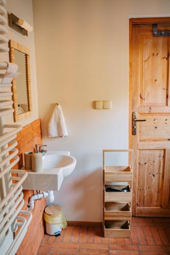a bathroom with a sink and a wooden door at tuŻur domki nad potokiem in Osie