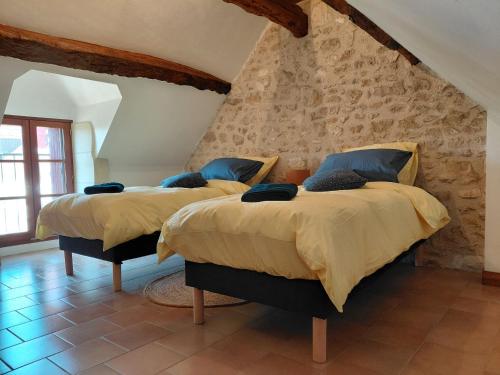 two beds in a room with a stone wall at Gites au fil des châteaux de la Loire in Saint-Georges-sur-Cher