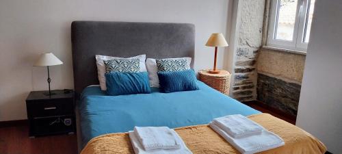 a bedroom with a bed with blue sheets and pillows at Casa da Muralha in Vila Nova de Foz Coa