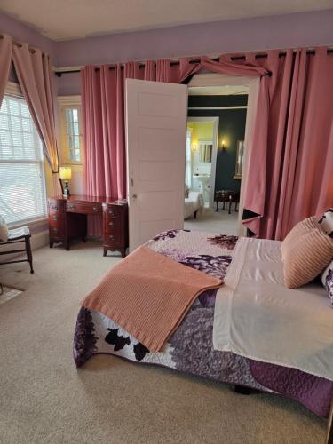 a bedroom with a large bed with pink curtains at The Kings Throne Inn and Guest House in Toledo