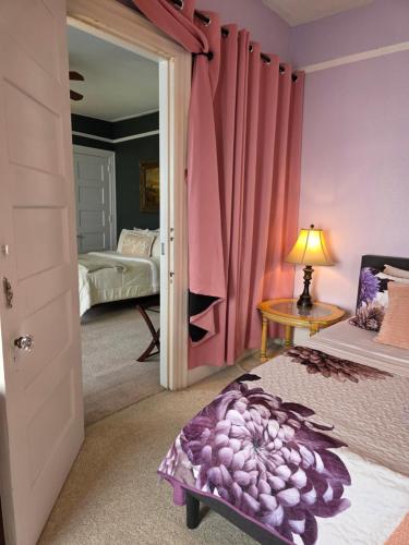 a bedroom with pink curtains and a bed and a table at The Kings Throne Inn and Guest House in Toledo