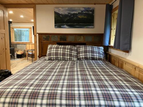 a bedroom with a bed with a plaid bedspread at Two Lakes Guesthouse in Seward