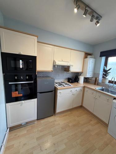 a kitchen with white cabinets and black appliances at Elegant 1-Bedroom Flat With Stunning Thames views in Kingston upon Thames