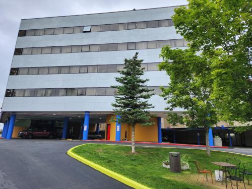 a building with a tree in front of it at Alex Hotel and Suites Anchorage Airport in Anchorage