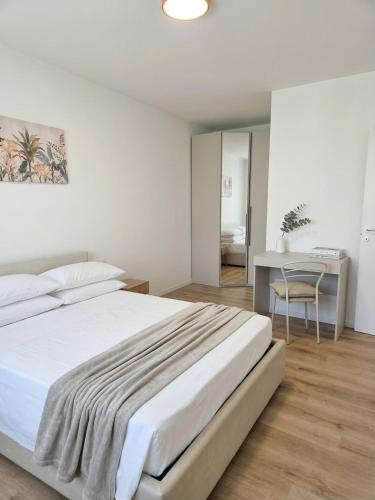 a white bedroom with a bed and a desk at Oasi Bernareggio Smart Work & Relax in Bernareggio